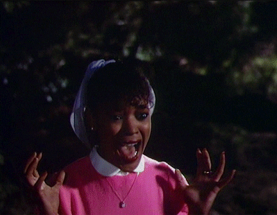 Gif de uma cena do videoclipe Thriller onde uma garota negra de casaco rosa grita assustada